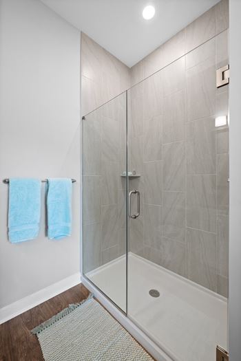 a glass shower with two blue towels in a bathroom